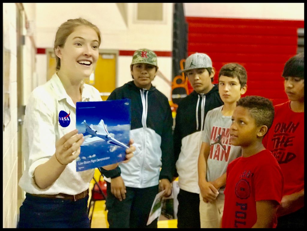 A woman wearing a NASA polo speaks with students at their school