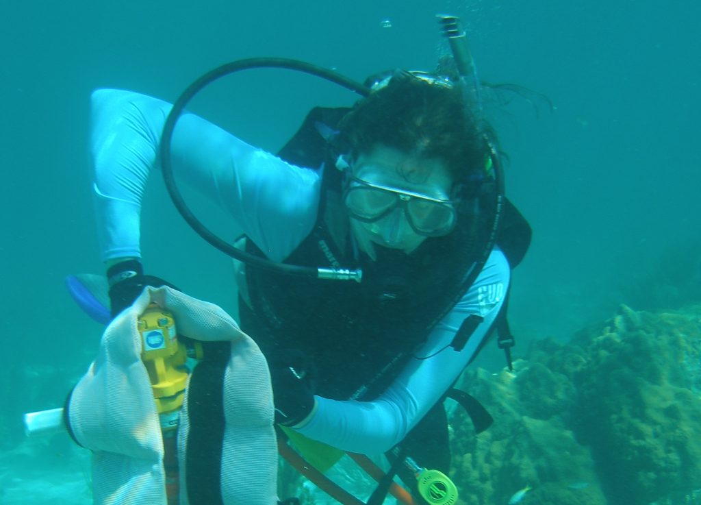 Dr. DeLong scuba diving holds equipment while swimming near a coral reef