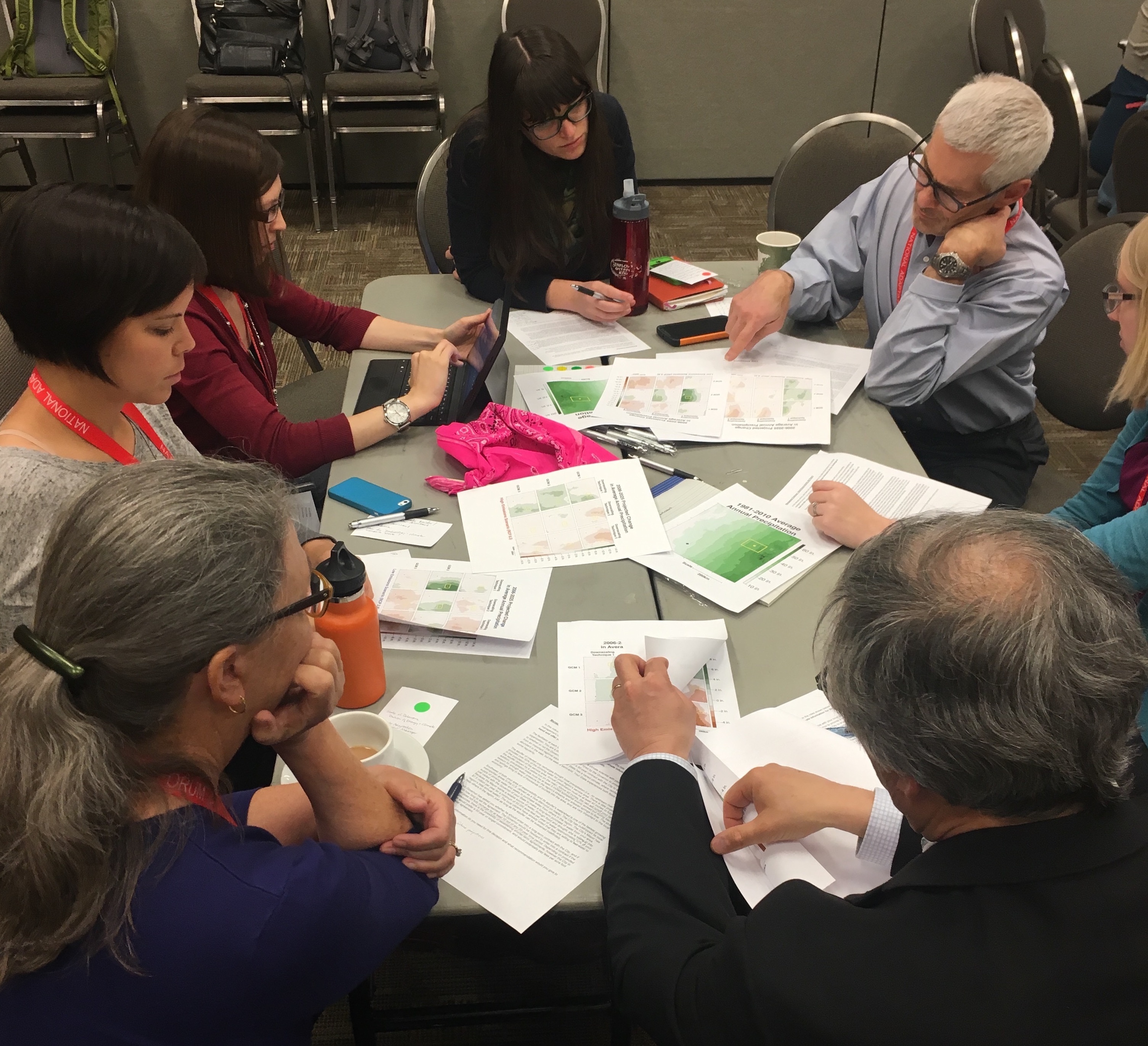 A group of people sitting at a table discussing charts on the table