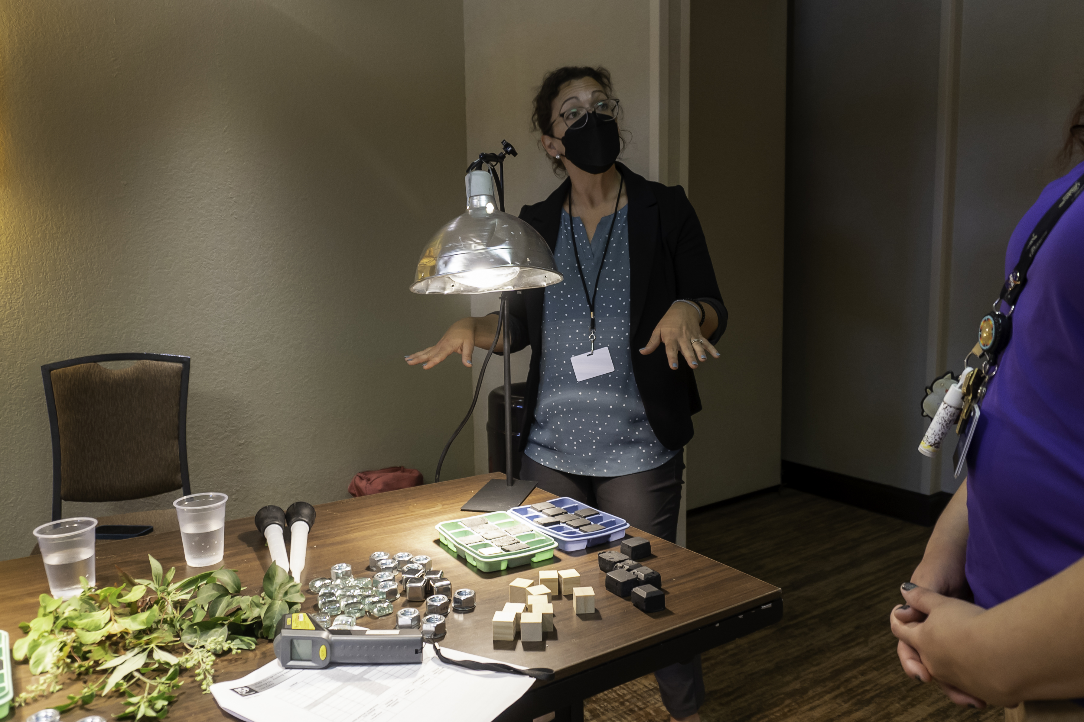 A person standing next to a table talking about the items on the table during the event.