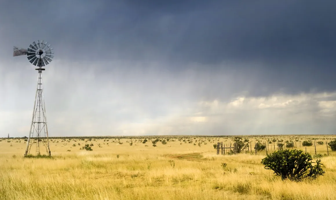 A a dry, grassy landscape with a dark, stormy sky