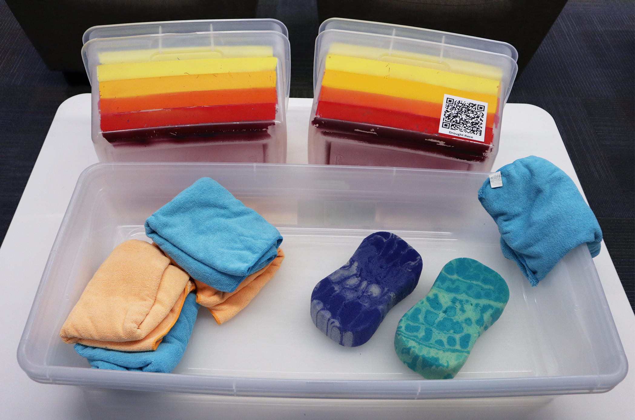 Several plastic buckets, rags, and sponges on a table