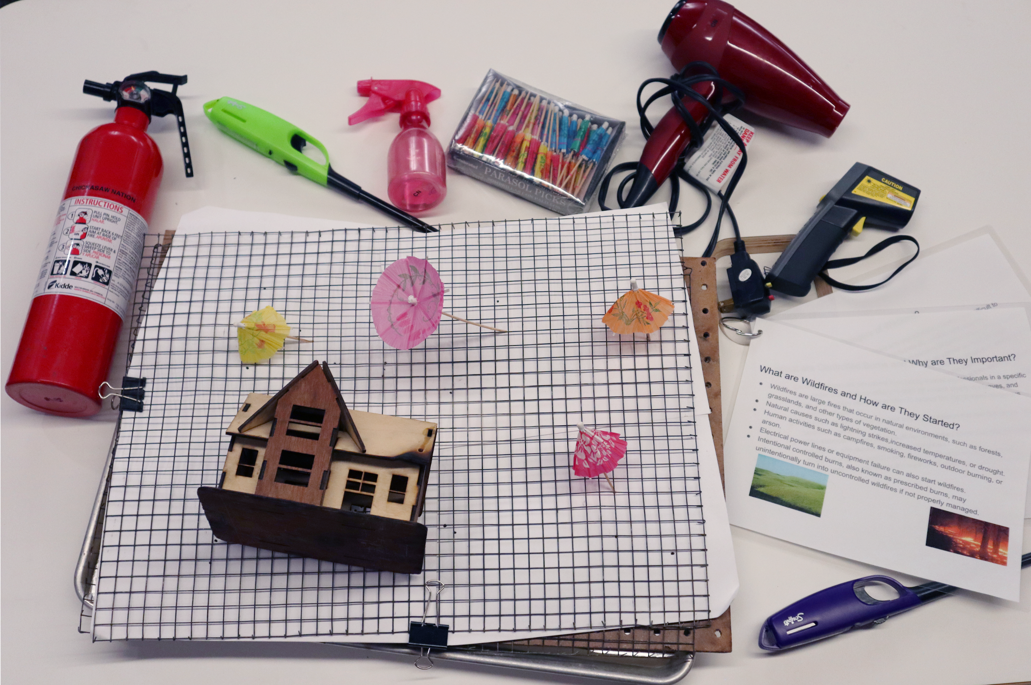 A spread of items used in the fire climatology activity, including a fire extinguisher, lighter, hair dryer, and combustable materials